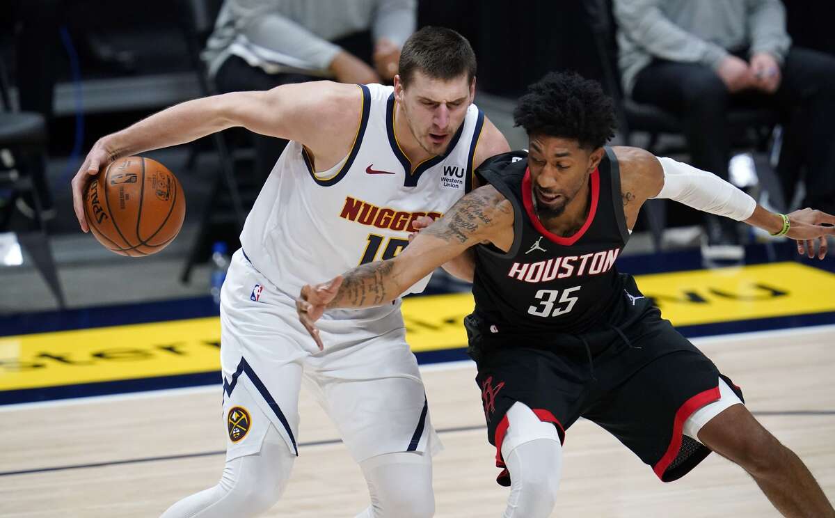 Denver Nuggets center Nikola Jokic, left, struggles to hold onto the ball as Houston Rockets forward Christian Wood defends in the first half of an NBA basketball game Monday, Dec. 28, 2020, in Denver. (AP Photo/David Zalubowski)