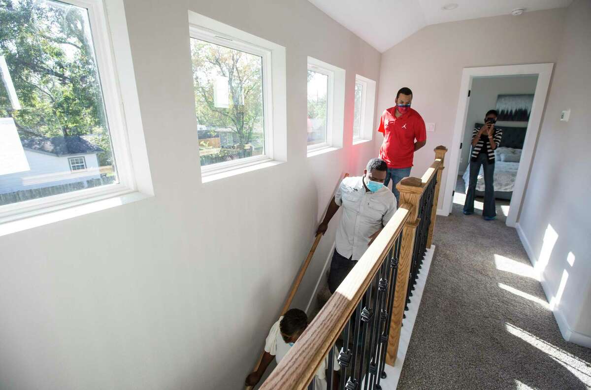 Ayesha Shelton, Kevan Shelton and Junious Williams walk down the stairs in one of the homes they have built in the Grand Park Square development Thursday, Nov. 12, 2020 in Houston. Shelton is developing homes in the Greater South Union area. Grand Park Square is meant to to inspire a new sense of community and drive to preserve and maintain the culture in the area as gentrification threatens other historic, underserved neighborhoods.
