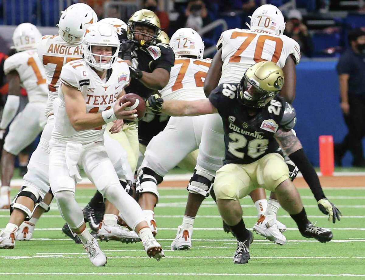Texas quarterback Sam Ehlinger (11) gets pursued by Colorado's Carson Wells (26) in the second quarter during the 2020 Valero Alamo Bowl at the Alamodome on Tuesday, Dec. 29, 2020.