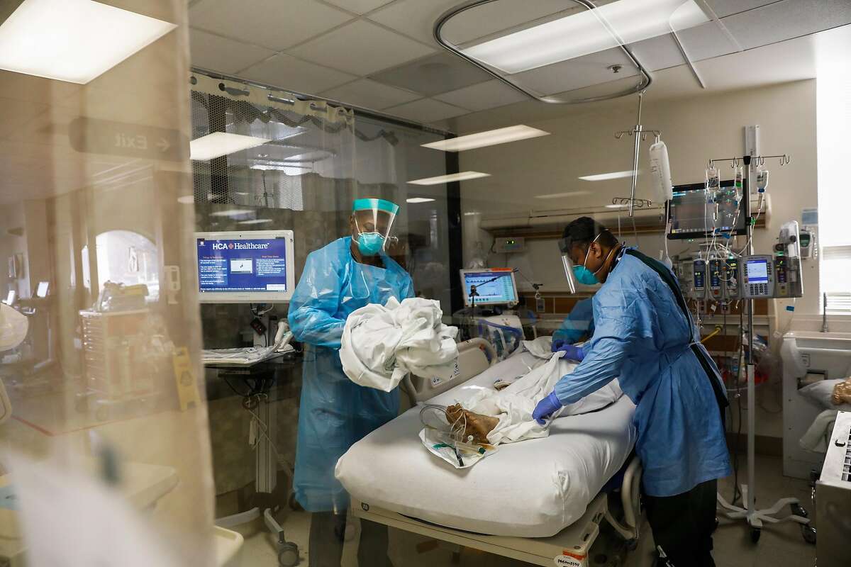 Waymond Jones (left) and Larry Ngiraswei help a patient in San Jose as hospital beds fill up.
