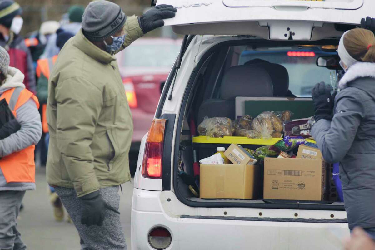 Volunteers load food into vehicles during a mass food distribution put on by Catholic Charities of the Diocese of Albany, and the Regional Food Bank of Northeastern New York at Watervliet High School on Wednesday, Dec. 30, 2020, in Watervliet, N.Y. (Paul Buckowski/Times Union)