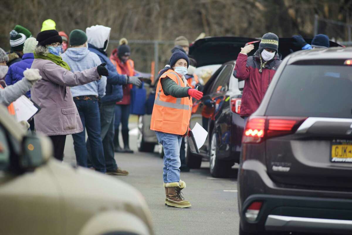 Volunteers direct drivers into the food delivery line during a mass food distribution put on by Catholic Charities of the Diocese of Albany, and the Regional Food Bank of Northeastern New York at Watervliet High School on Wednesday, Dec. 30, 2020, in Watervliet, N.Y. (Paul Buckowski/Times Union)