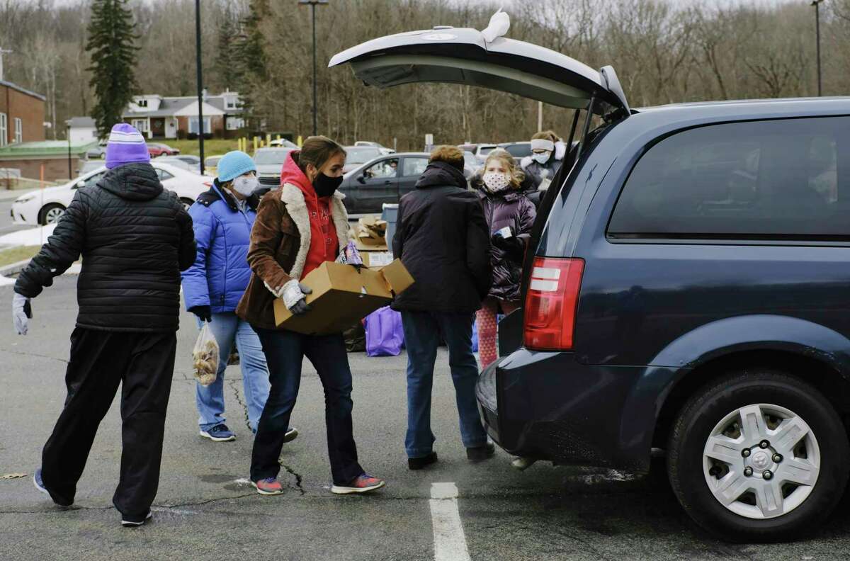 Volunteers load food into vehicles during a mass food distribution put on by Catholic Charities of the Diocese of Albany, and the Regional Food Bank of Northeastern New York at Watervliet High School on Wednesday, Dec. 30, 2020, in Watervliet, N.Y. (Paul Buckowski/Times Union)