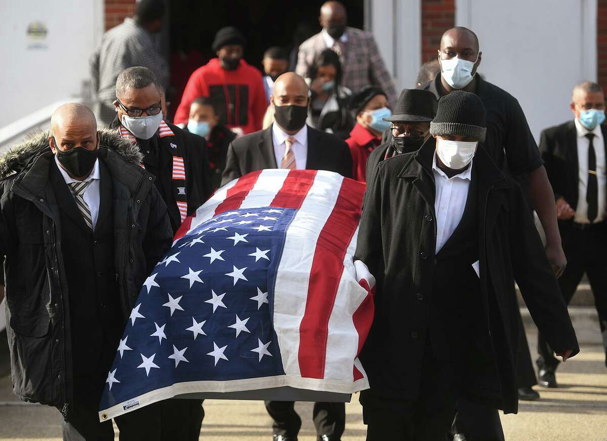 Draped in the American flag, the casket of State Senator Ed Gomes is carried from his funeral service at Blessed Sacrament RC Church on Union Avenue in Bridgeport, Conn. on Wednesday, December 30, 2020.