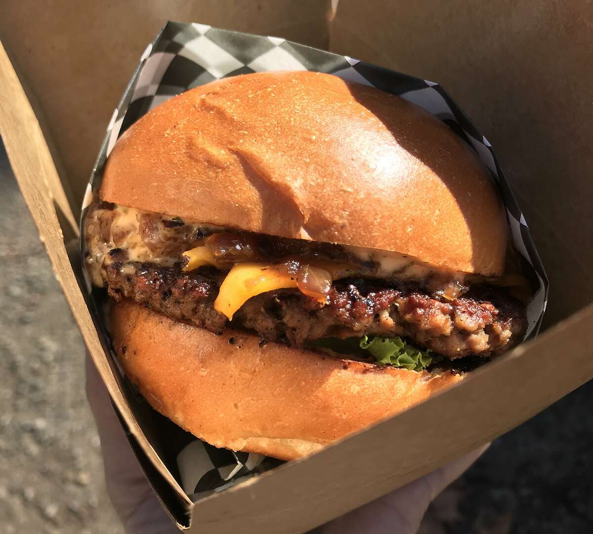 An Impossible Burger topped with vegan American cheese and caramelized onions from Malibu's Burgers, an all-vegan restaurant in Oakland.