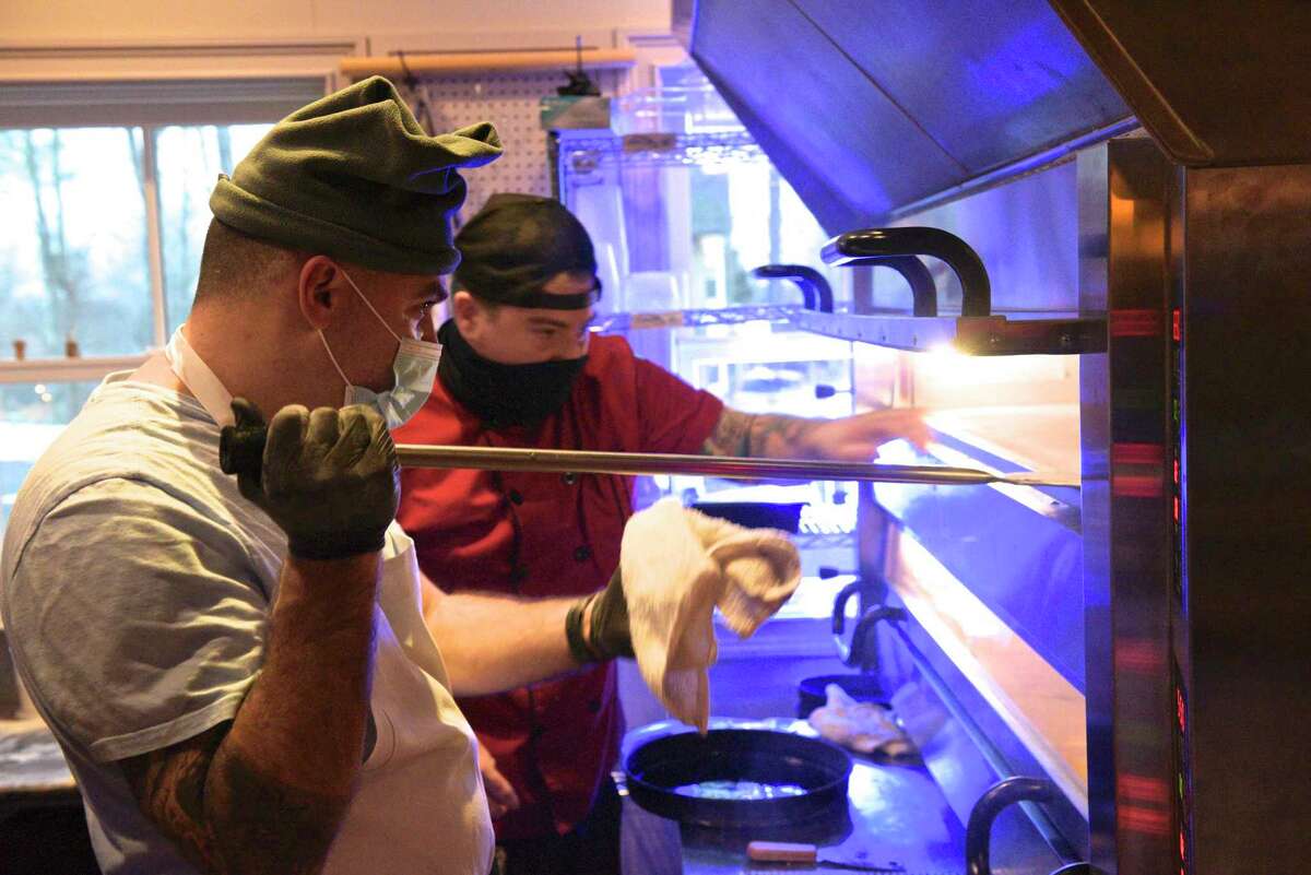 Pizza Guys Matteo Stanz, left, and Dan Rooney check on a pizza in the oven at Good Old Days Pizzeria and Cocktail Den, in the lower level of Marygold's on Main. The restaurant had its opening night on Wednesday, December 30, 2020, in Newtown. Conn.