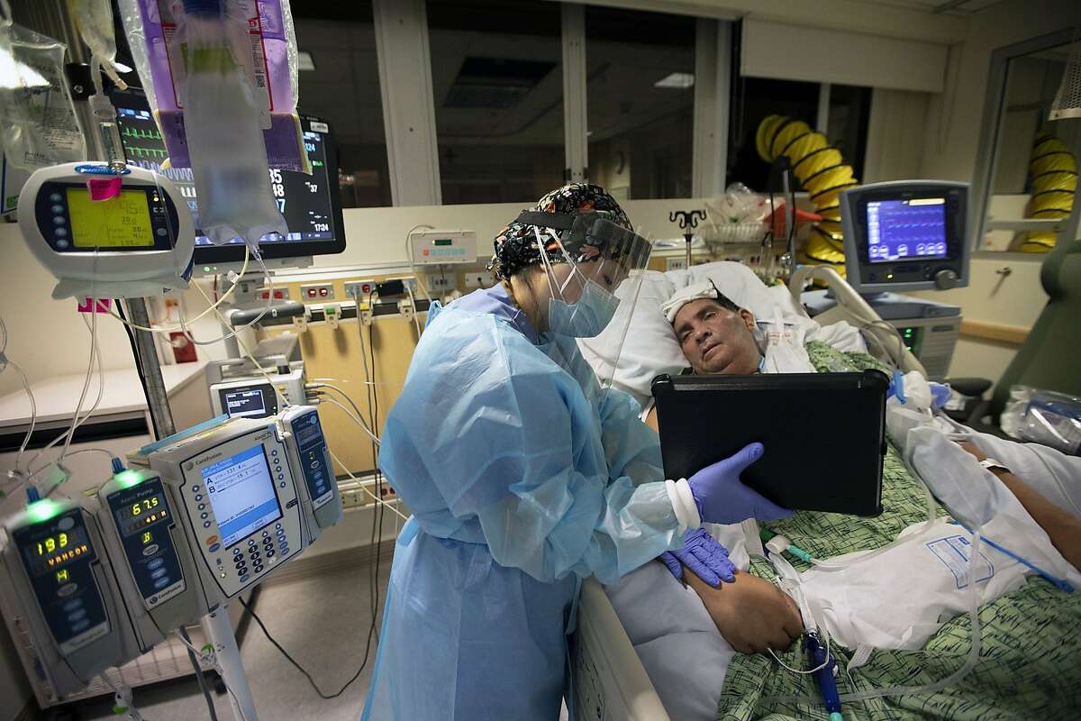 在富勒顿(奥兰治县)的普罗维登斯圣裘德医疗中心，护士Kat Yi拿着iPad，让50岁的病人Eduardo Rojas和他的妻子Angelica可以交谈。