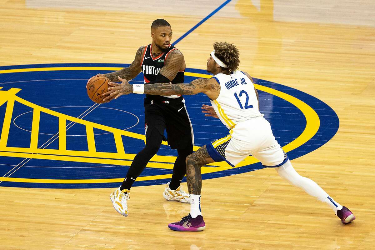 Portland Trailblazers guard Damian Lillard (0) looks to pass the ball as Golden State Warriors guard Kelly Oubre Jr. (12) defends during the first quarter of a NBA basketball game on Friday, Jan. 1, 2021 in San Francisco, Calif..