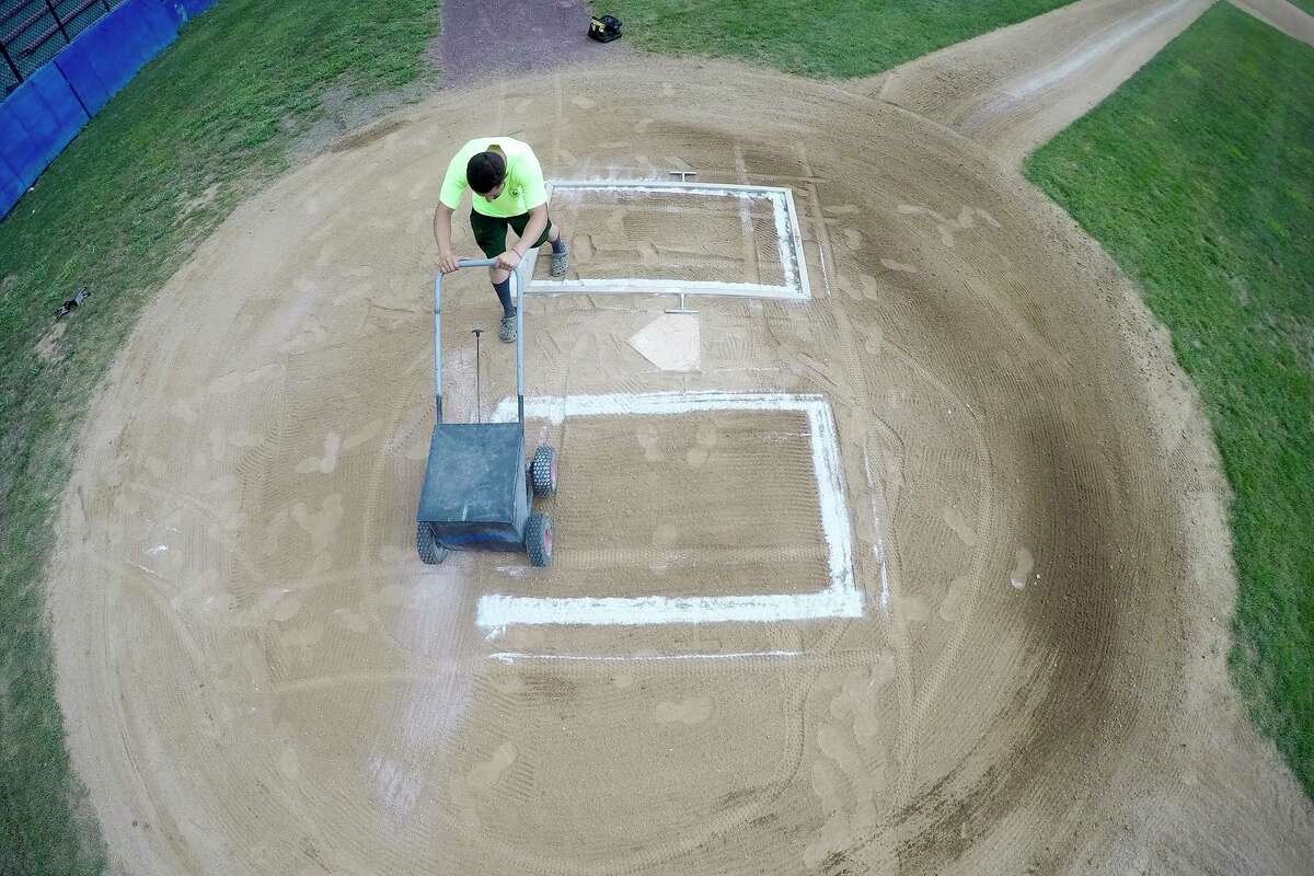 Mike Pinto, an employee with the City of Stamford Parks and Recreation Department layouts and stripes the batters box at Cubeta Stadium in preparation for games on July 28, 2020 in the Stamford Babe Ruth Baseball League in Stamford, Connecticut.