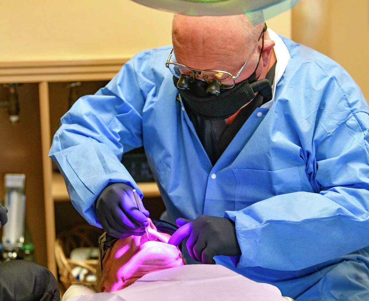 Dentist Dr. Philip Miner is wearing a JustAir powered air-purifying respirator as he works on a patient Thursday, Dec. 3, 2020.