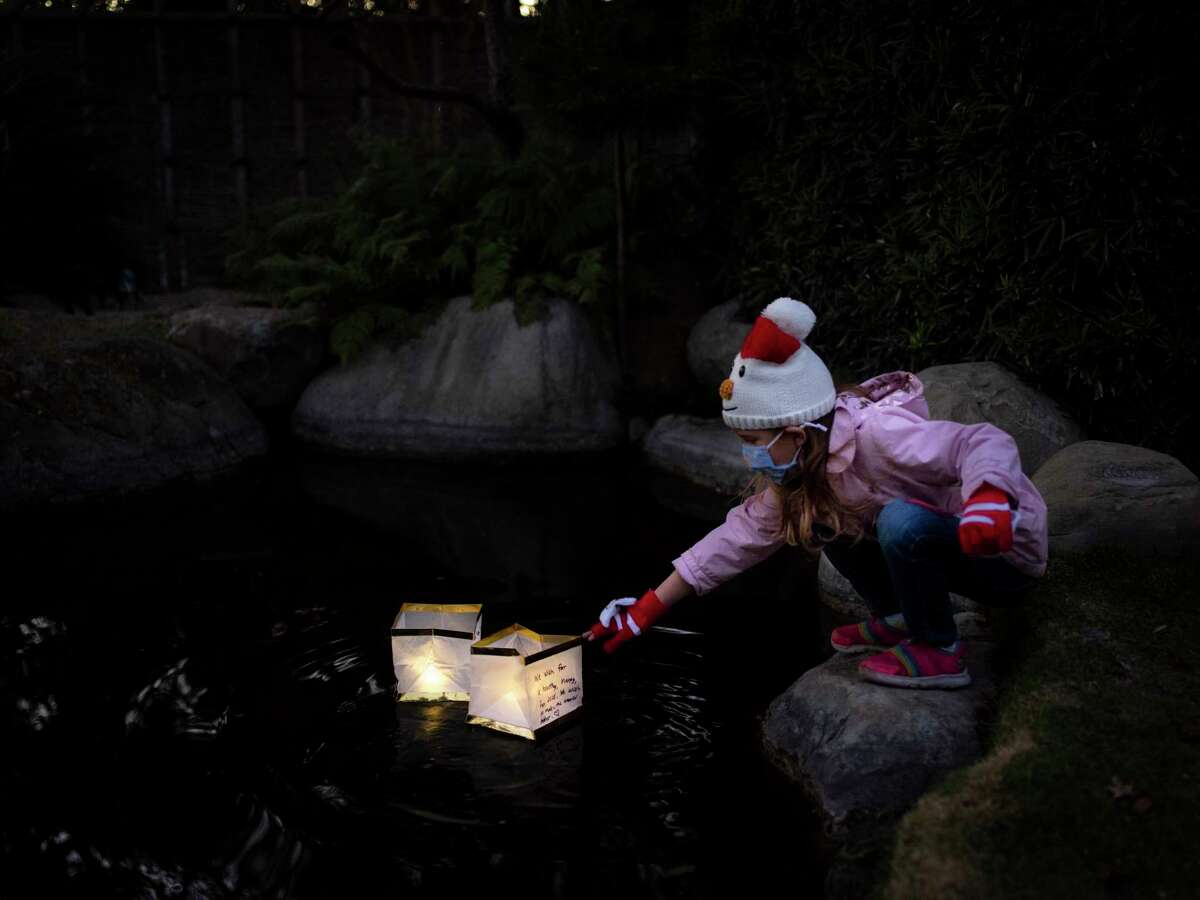 Scarlett Reed, 6, drops her lantern bearing a wish for the new year into the pond at the San Antonio Botanical Garden.