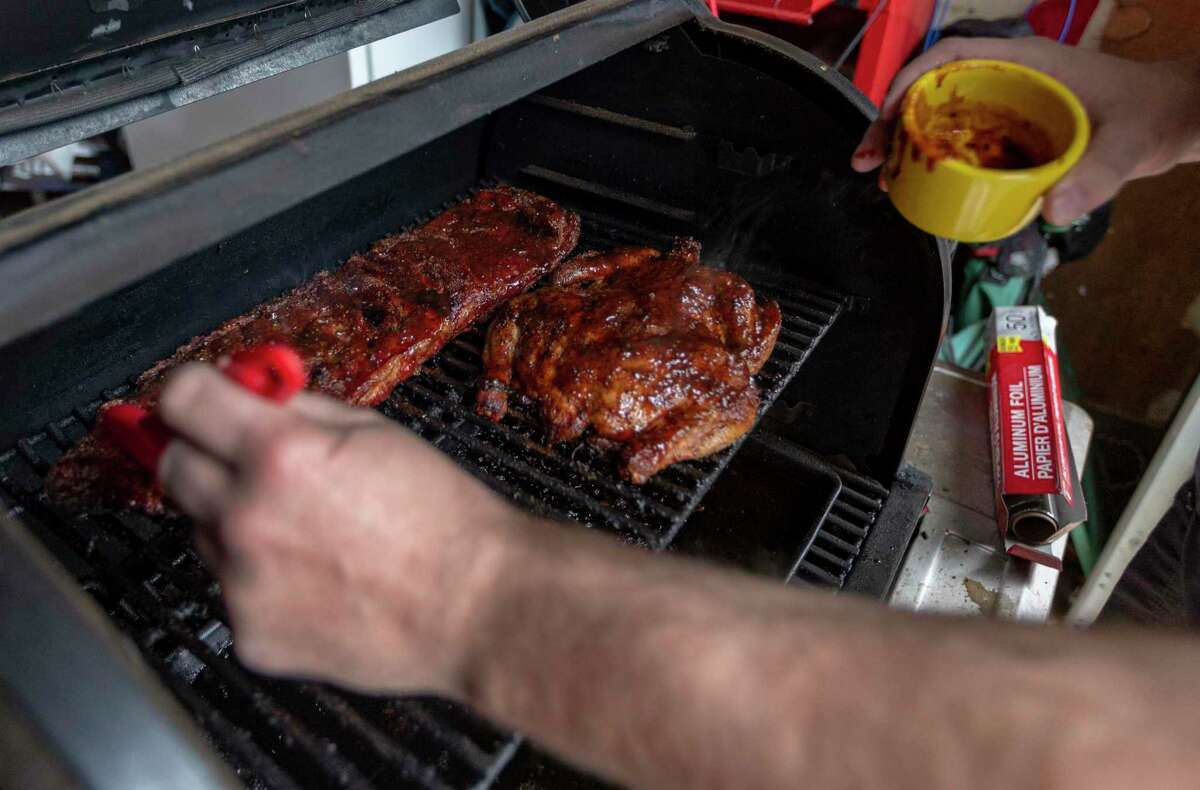 Chuck Blount applies barbecue sauce to chicken and ribs. Blount recommends only basting with sauce in the last 10 minutes of cooking to prevent the sauce from burning.