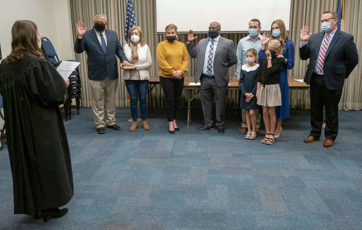 MISD new board members and returning members, Robert Marquez, with his wife Delia, Michael Booker, with his wife, Austin, Katie Joyner with her family, Dave, Willa and Fay and Bryan Murry raise their right hand as Judge Leah Robertson administers their oath of office 01/04/2021 in the MISD Administration Building. Tim Fischer/Reporter-Telegram