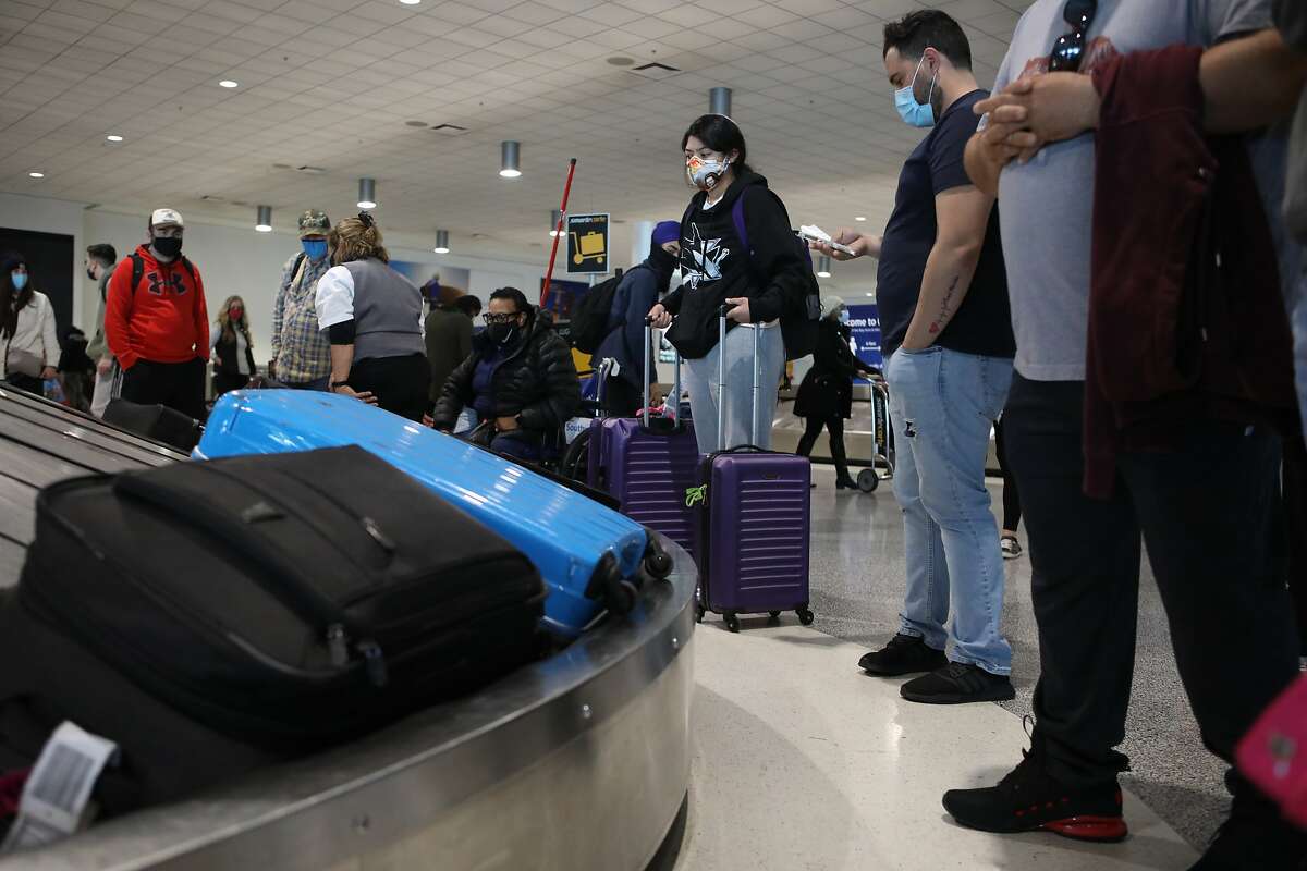 Travelers wait to pick up their bags after their arrival at Oakland International Airport on Dec. 22, 2020.