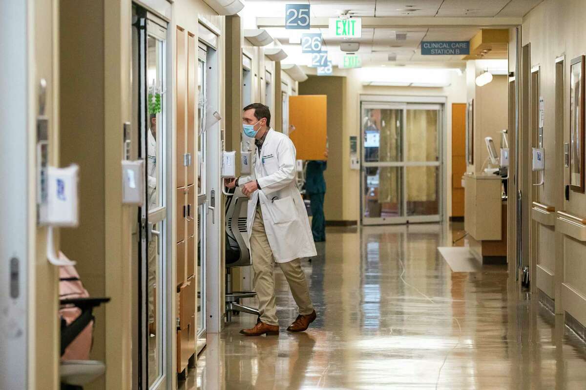A doctor walks into one of the few non-COVID rooms remaining in a Houston Methodist ICU that has been converting rooms to serve an increase in COVID patients, Tuesday, Jan. 5, 2021, in Houston's Texas Medical Center. This particular ICU traditionally serves cardiac patients, but currently 20 out of its 30 beds have COVID patients, according to Dr. Faisal Masud, medical director of critical care at Houston Methodist. By the end of the week, Masud expects almost the entire unit to be COVID patients.