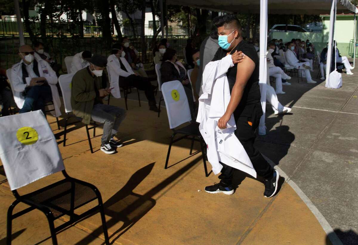 Un trabajador de la salud sostiene su brazo donde recibió una inyección de la vacuna Pfizer-BioNTech para el COVID-19 antes de tomar asiento en un área de observación en la base militar N-1 en la Ciudad de México, el miércoles 30 de diciembre de 2020.