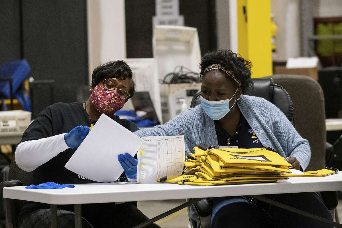 Elections workers at the Fulton County Georgia elections warehouse check in voting machine memory cards that store ballots following the Senate runoff election in Atlanta on Tuesday, Jan. 5, 2021. Georgia's two Senate runoff elections on Tuesday will determine which party controls the U.S. Senate. Republican Kelly Loeffler is going up against Democrat Raphael Warnock, while Republican David Perdue is challenging Democrat Jon Ossoff. Democrats must win both seats to take control of the Senate. (AP Photo/Ben Gray)