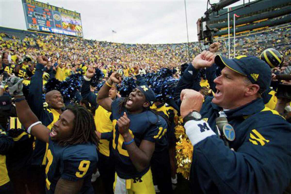 Michigan wide receiver Martavious Odoms (9), quarterback Denard Robinson (16), and coach Rich Rodriguez, right, sing the fight song with teammates and fans after an NCAA college football game with Connecticut, Saturday, Sept. 4, 2010, in Ann Arbor. Michigan won 30-10. (AP Photo/Tony Ding)