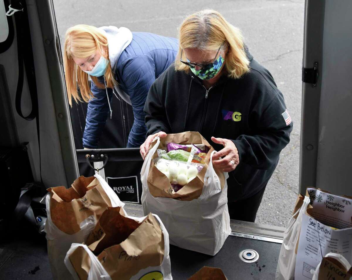 TAG assistant Sydney Orszulak, left, and TAG Executive Director Debbie Vetromile load a van with food outside for Neighbor to Neighbor clients. The nonprofit has moved into its new temporary location downtown and is looking for help from the community.