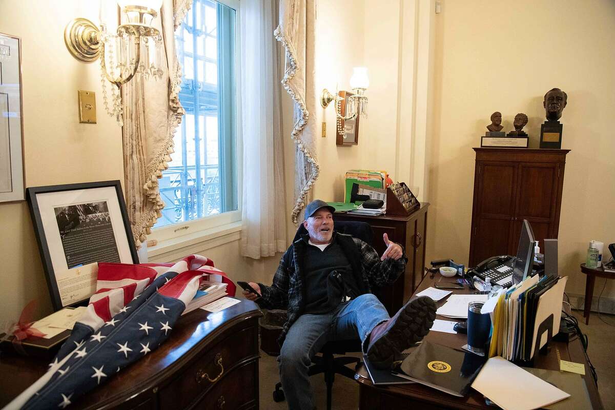 A supporter of President Donald Trump sits inside the office of US Speaker of the House Nancy Pelosi as Trump supporters stormed the US Capitol in Washington, DC, January 6, 2021.