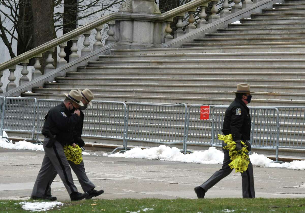 New York State Troopers clear crime tape from East Capitol Park following a stabbing which took place during a clash between protesters on Wednesday, Jan. 6, 2021, in Albany, N.Y. Police say two people were taken to Albany Medical Center Hospital for treatment and one person is in custody. (Will Waldron/Times Union)