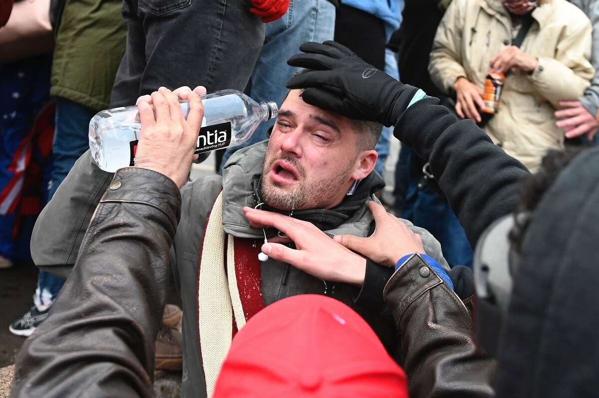 A Trump supporter helps a man tear-gassed as they gather across from the US Capitol on January 6, 2021, in Washington, DC.
