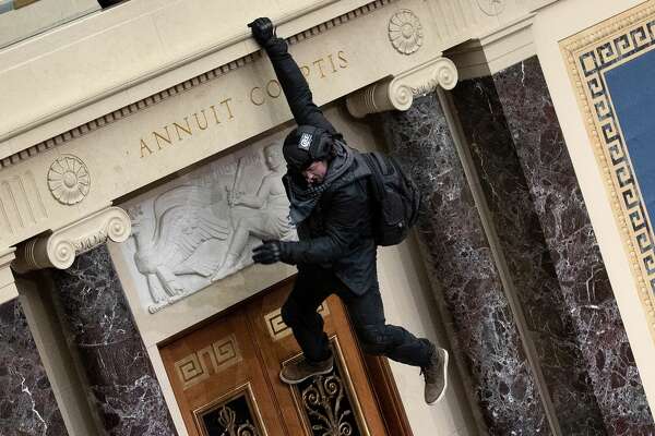 WASHINGTON, DC - JANUARY 06: A protester supporting U.S. President Donald Trump jumps from the public gallery to the floor of the Senate chamber at the U.S. Capitol Building on January 06, 2021 in Washington, DC. Congress held a joint session today to ratify President-elect Joe Biden's 306-232 Electoral College win over President Donald Trump. A group of Republican senators said they would reject the Electoral College votes of several states unless Congress appointed a commission to audit the election results (Photo by Win McNamee/Getty Images)