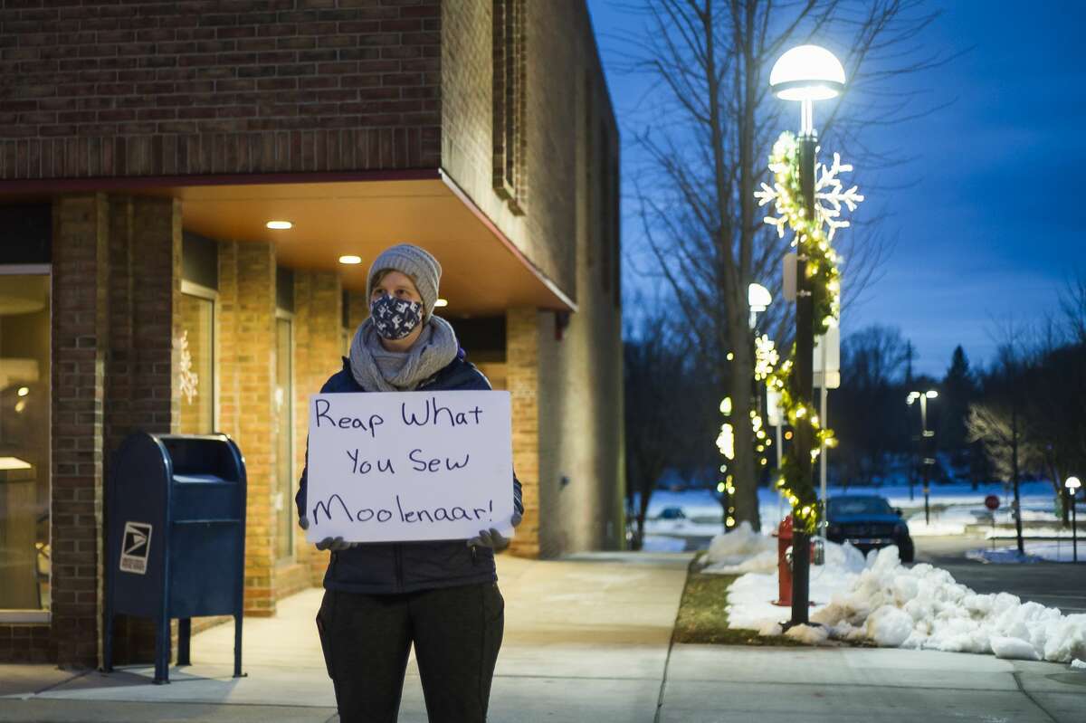 Jennifer Austin holds a sign as a small group of people gather outside the Midland office of U.S. Rep. John Moolenaar Wednesday, Jan. 6, 2021 to protest his support of the president after a pro-Trump mob breached the U.S. Capitol in Washington D.C. hours earlier. (Katy Kildee/kkildee@mdn.net)