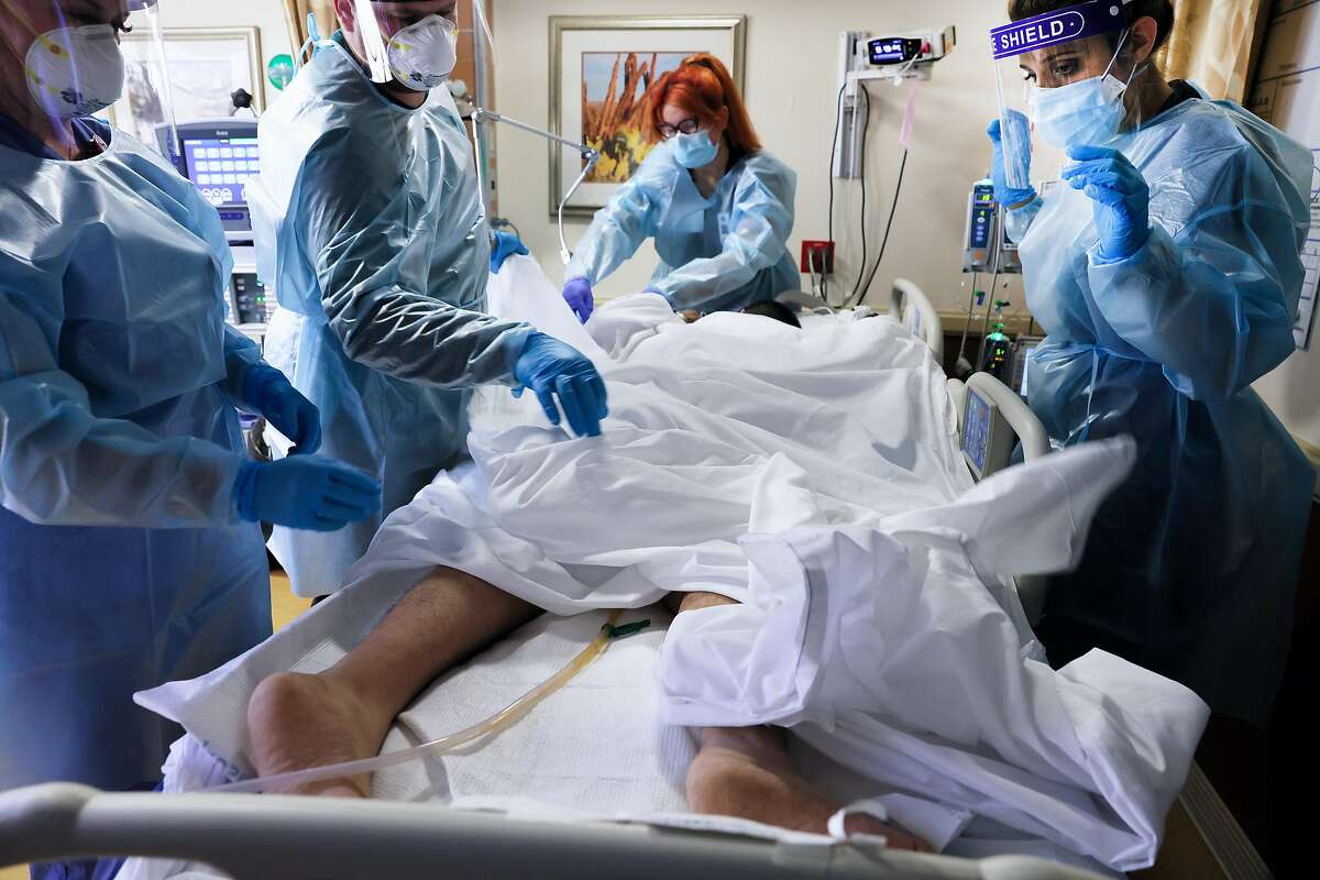 Clinicians prepare to re-position a COVID-19 patient into the supine position at Providence St. Mary Medical Center amid a surge in COVID-19 patients at the hospital and across Southern California on January 6, 2021 in Apple Valley, California. The hospital is operating at over 200 percent of its normal ICU (Intensive Care Unit) capacity and is currently converting some patient rooms into ICU rooms to treat the increase in COVID-19 patients requiring ICU-level care. California has issued a new directive ordering hospitals with space to accept patients from other hospitals which have run out of ICU beds due to the coronavirus pandemic.