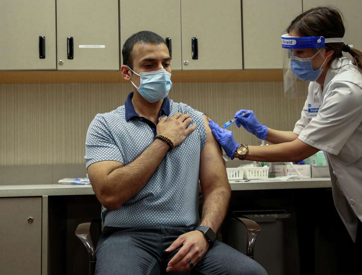 Pharmacist Stephanie Phan, right, administers a dose of a COVID-19 vaccine to Nabeel Sattar, pharmacy manager, at the Kroger located at 1440 Studemont Street, on Wednesday, Jan. 6, 2021, in Houston.