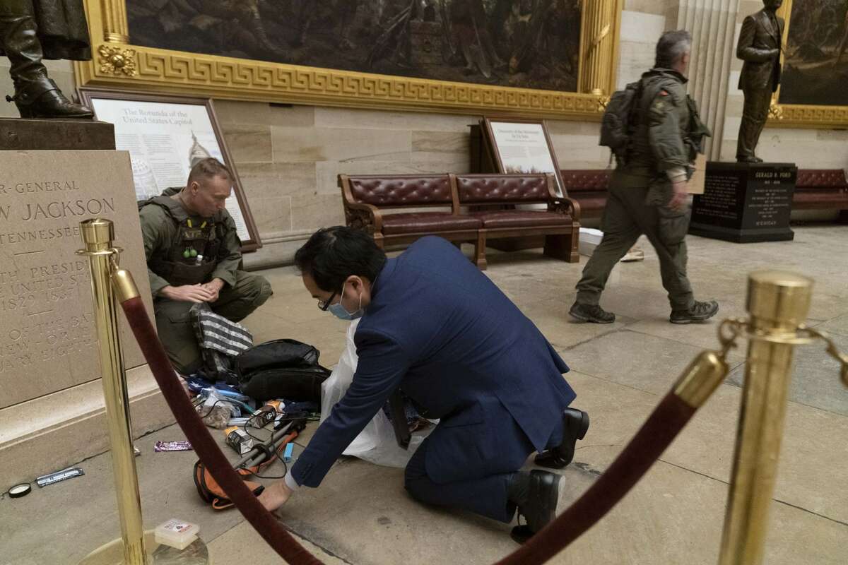 Rep. Andy Kim, D-N.J., helps ATF police officers clean up debris and personal belongings strewn across the floor of the Rotunda in the early morning hours of Thursday, Jan. 7, 2021, after protesters stormed the Capitol in Washington, on Wednesday. (AP Photo/Andrew Harnik)