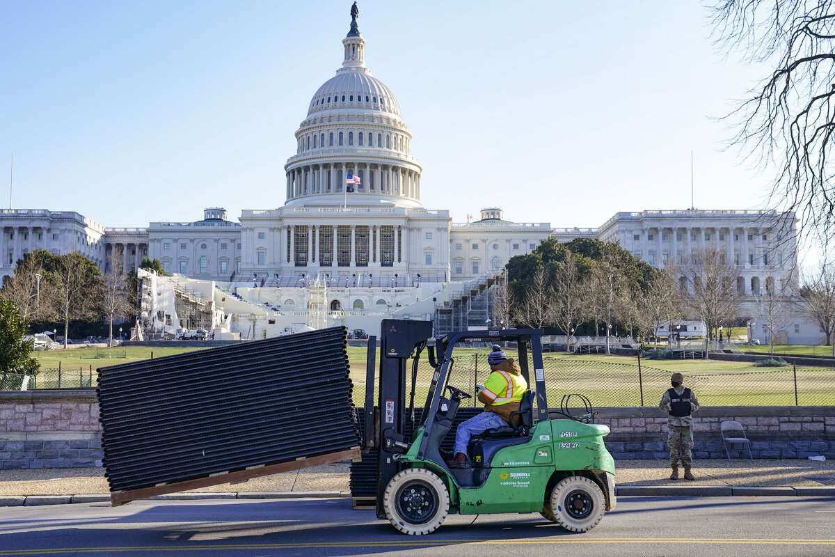 DC National Guard stands outside a mostly quiet Capitol, Thursday morning, Jan. 7, 2021 in Washington, as workers place security fencing in place. The House and Senate certified the Democrat's electoral college win early Thursday after a violent throng of pro-Trump rioters spent hours Wednesday running rampant through the Capitol. A woman was fatally shot, windows were bashed and the mob forced shaken lawmakers and aides to flee the building, shielded by Capitol Police. (AP Photo/John Minchillo)