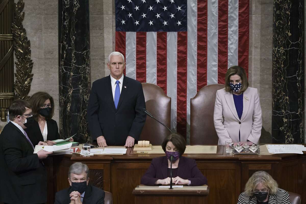 Vice President Mike Pence and Speaker of the House Nancy Pelosi, D-Calif., read the final certification of Electoral College votes cast in November's presidential election during a joint session of Congress after working through the night, at the Capitol in Washington, Thursday, Jan. 7, 2021. Violent protesters loyal to President Donald Trump stormed the Capitol Wednesday, disrupting the process. (AP Photo/J. Scott Applewhite, Pool)