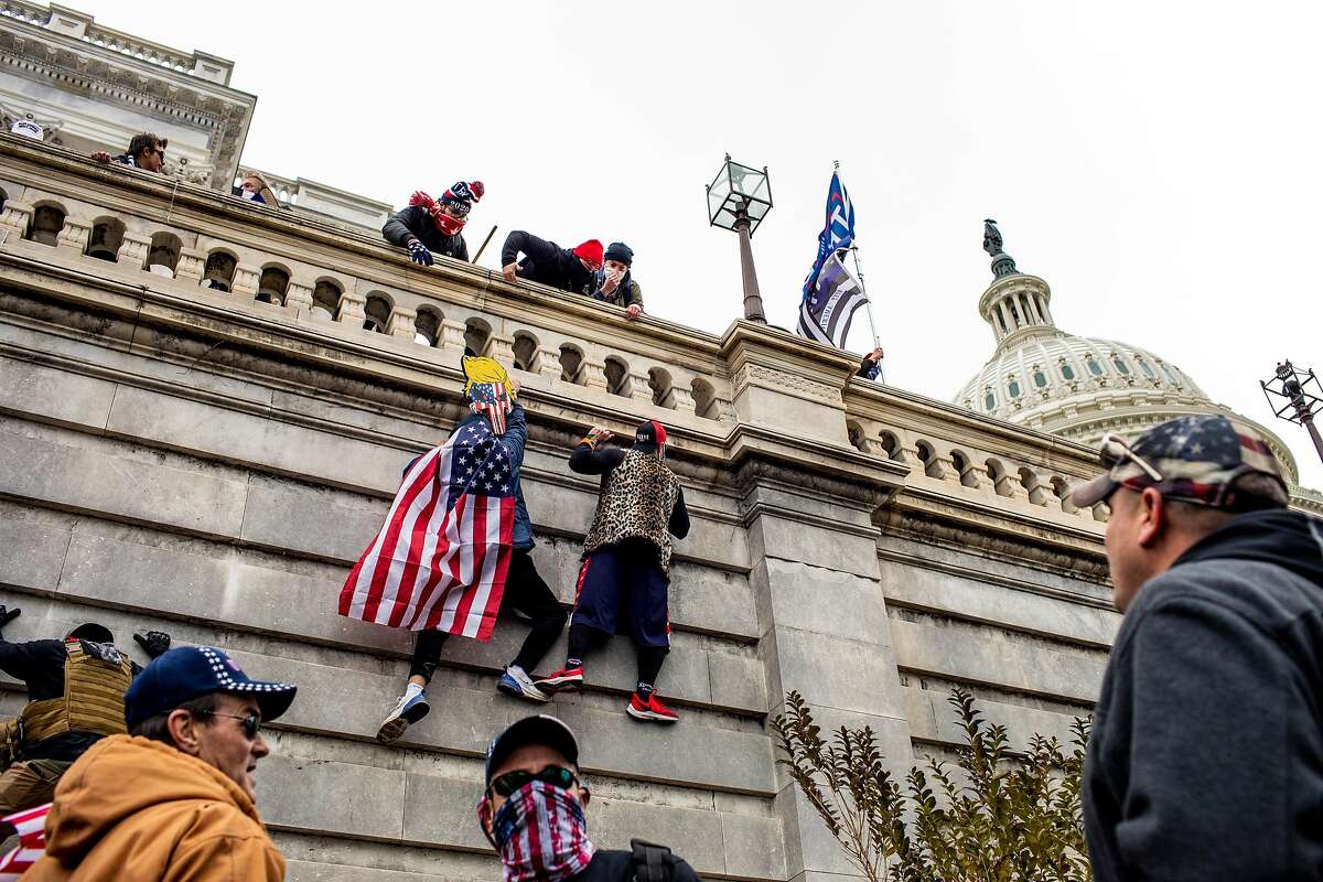 Supporters of President Donald Trump scale a wall on the Senate side of the Capitol Building in an attempt to disrupt the certification of the Electoral College results, Jan. 6, 2021. The mob in Washington attempting to disrupt the peaceful transition of American power also posed a threat to all democracies.
