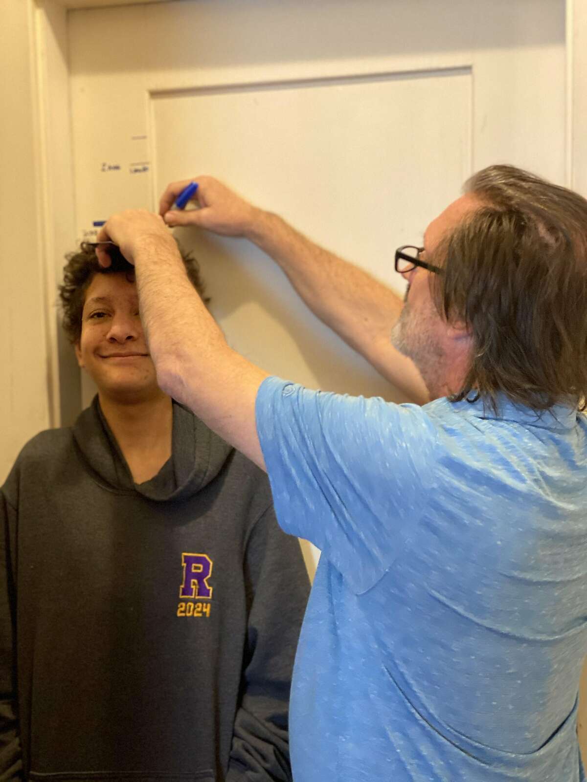 Aidan Fisher-Paulson gets his height measured by his father, Brian, during the family's annual Talling of the Boys on January 1, 2021.