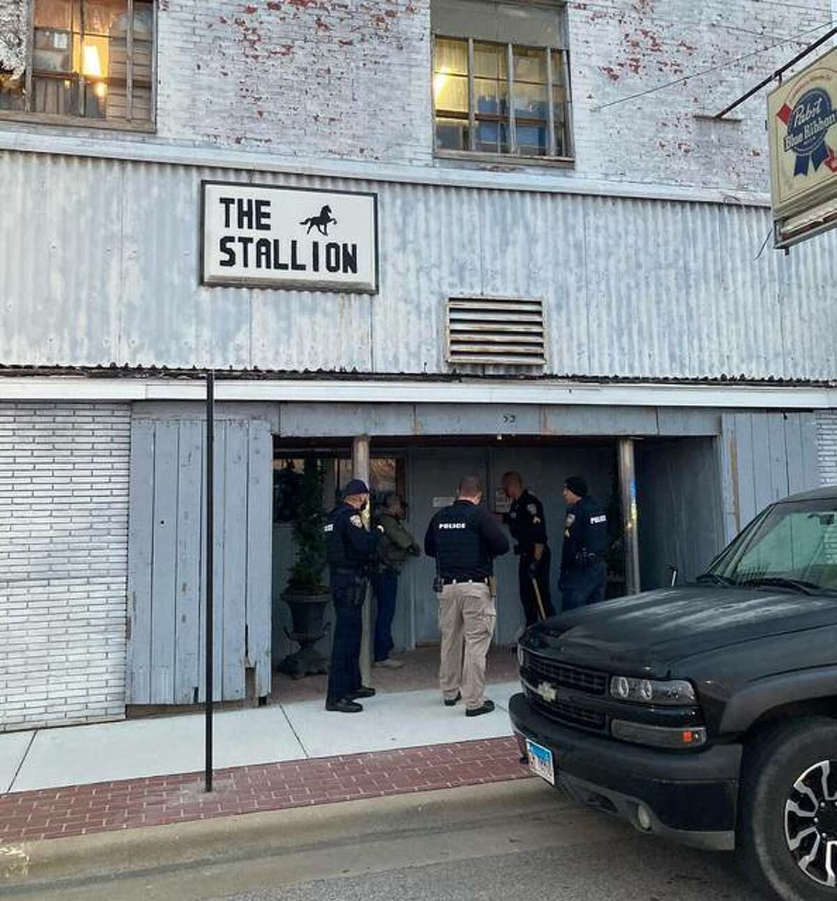 Law enforcement officers stand outside The Stallion Bar in Wood River on Dec. 23. Officials last month deemed the building uninhabitable. On Thursday, the city revoked the bar’s liquor license.