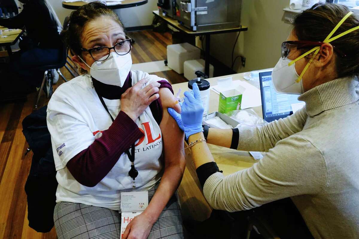 Micky Jimenez, left, executive director of Capital District LATINOS, receives her first dose of a COVID-19 vaccine from R.N. Cristina Baglio at a vaccination distribution site on Wednesday, Jan. 6, 2021, in Albany, N.Y. (Paul Buckowski/Times Union)