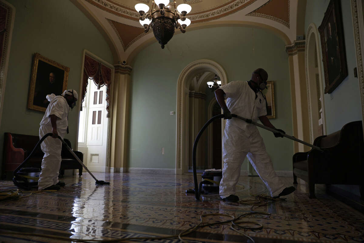 A cleaning crew vacuums the floor of a hallway at the U.S. Capitol January 7, 2021 in Washington, DC. The U.S. Congress has finished the certification for President-elect Joe Biden and Vice President-elect Kamala Harris' electoral college win after pro-Trump mobs stormed the Capitol and temporarily stopped the process.