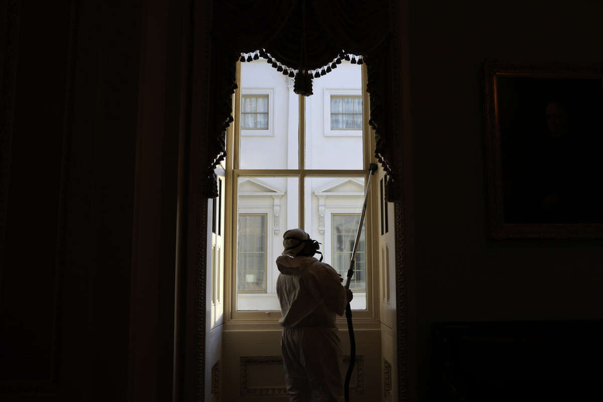 A member of a cleaning crew vacuums a window at the U.S. Capitol January 7, 2021 in Washington, DC. The U.S. Congress has finished the certification for President-elect Joe Biden and Vice President-elect Kamala Harris' electoral college win after pro-Trump mobs stormed the Capitol and temporarily stopped the process.