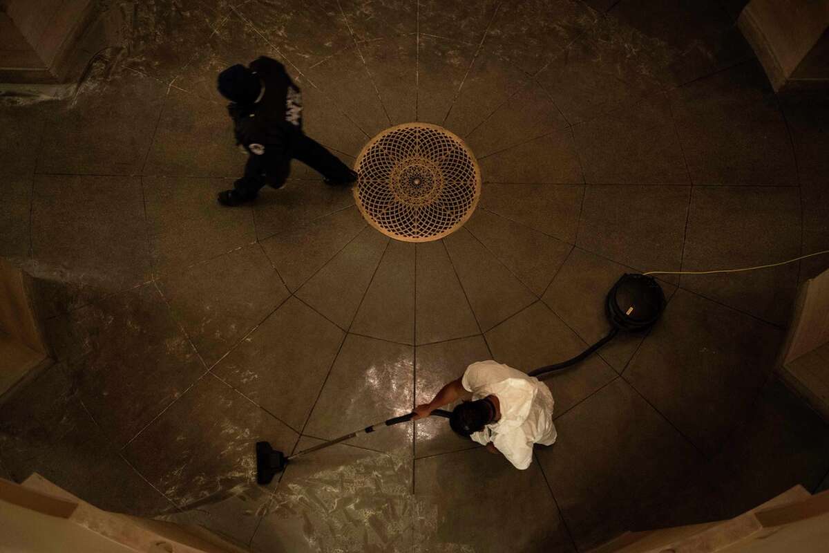 A Capitol Police officer walks past a worker cleaning damage a day after a pro-Trump mob broke into the US Capitol on January 7, 2021, in Washington, DC. (Photo by Brendan Smialowski / AFP)
