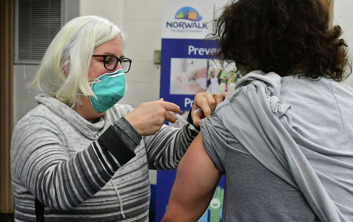 Volunteer Patricia Carey administers the COVID vaccine to an employee of Silver Living senior residence at the Norwalk Senior Center Friday, in Norwalk.