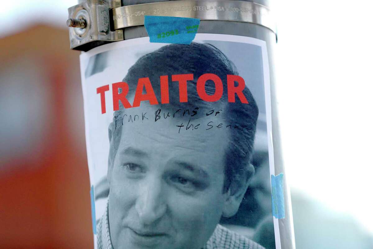 A protester writes on a photo of Senator Ted Cruz as he joined other Houston activists for a demonstration at the Leland Federal Building, in Houston, Thursday, Jan. 7, 2021, against the Trump supporters' disruption of Congress yesterday. The demonstration was organized by the Houston Socialist Movement, Houston United Front against Fascism, and People's New Black Panther Party.