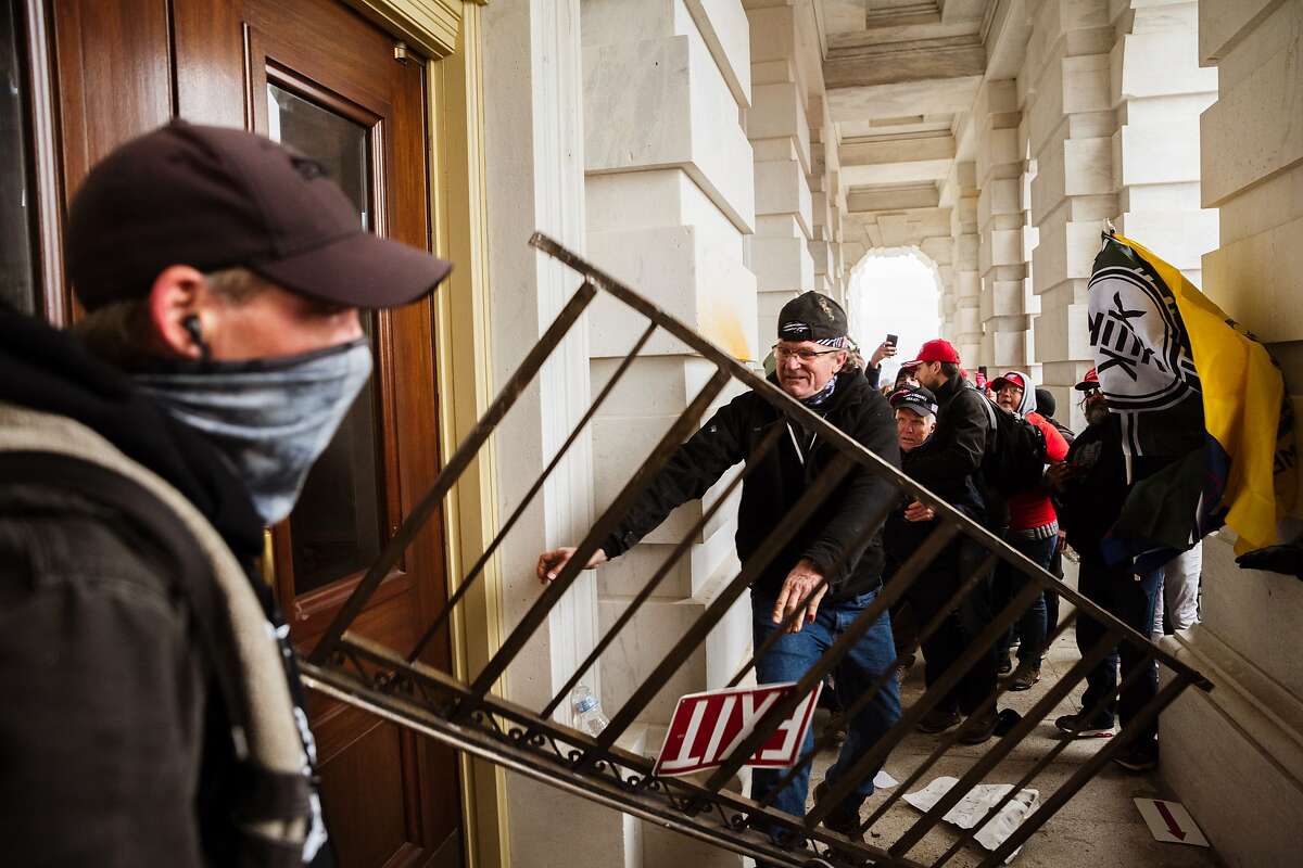 WASHINGTON, DC - JANUARY 06: A member of a pro-Trump mob bashes an entrance of the Capitol Building in an attempt to gain access on January 6, 2021 in Washington, DC. A pro-Trump mob stormed the Capitol, breaking windows and clashing with police officers. Trump supporters gathered in the nation's capital today to protest the ratification of President-elect Joe Biden's Electoral College victory over President Trump in the 2020 election. (Photo by Jon Cherry/Getty Images)