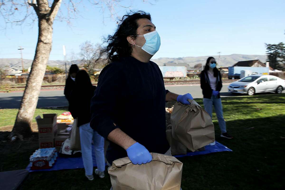 Paymon Shariat-Panah carries bags of food to community members at Charles F. Kennedy Park in Union City.