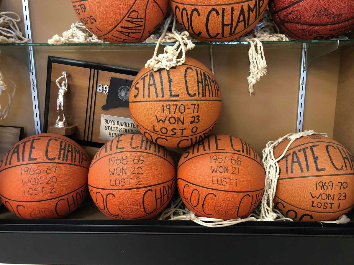Game balls from Cromwell's five consecutive championship victories adorn the trophy case just outside the Jake Salafia Gymnasium at Cromwell High.