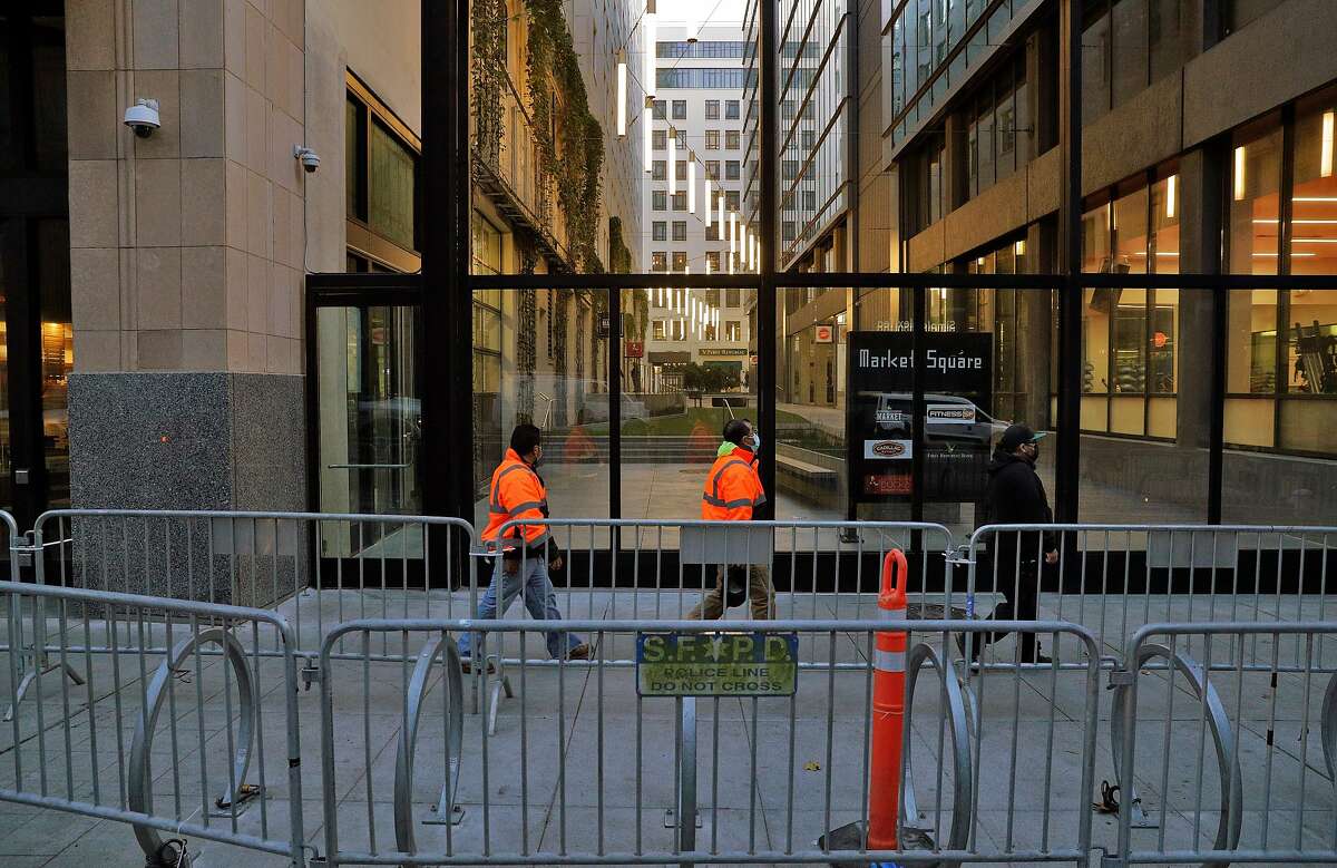 Pedestrians walks by Market Square near Twitter headquarters behind barricades placed in anticipation of supporters of President Donald Trump protesting outside later during a planned gathering in San Francisco, Calif., on Monday, January 11, 2021. The social media company suspended the president earlier in the week following the violent takeover of The United States Capitol last week by his supporters.