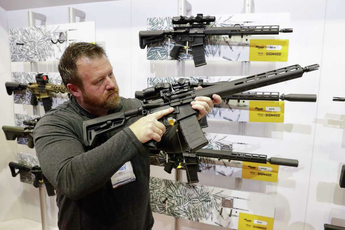 FILE - Bryan Oberc, Munster, Ind., tries out an AR-15 from Sig Sauer in the exhibition hall at the National Rifle Association Annual Meeting in Indianapolis, Saturday, April 27, 2019. Efforts to impose restrictions on firearms will soon have a supporter in the White House. But it's unlikely that big ticket items gun-control advocates have pined for will have much chance of passage given the tight margins in Congress and the increased polarization over gun issues. Much has changed in the past 12 years: more Americans own firearms and there are more AR-platform firearms in the civilian market. (AP Photo/Michael Conroy)