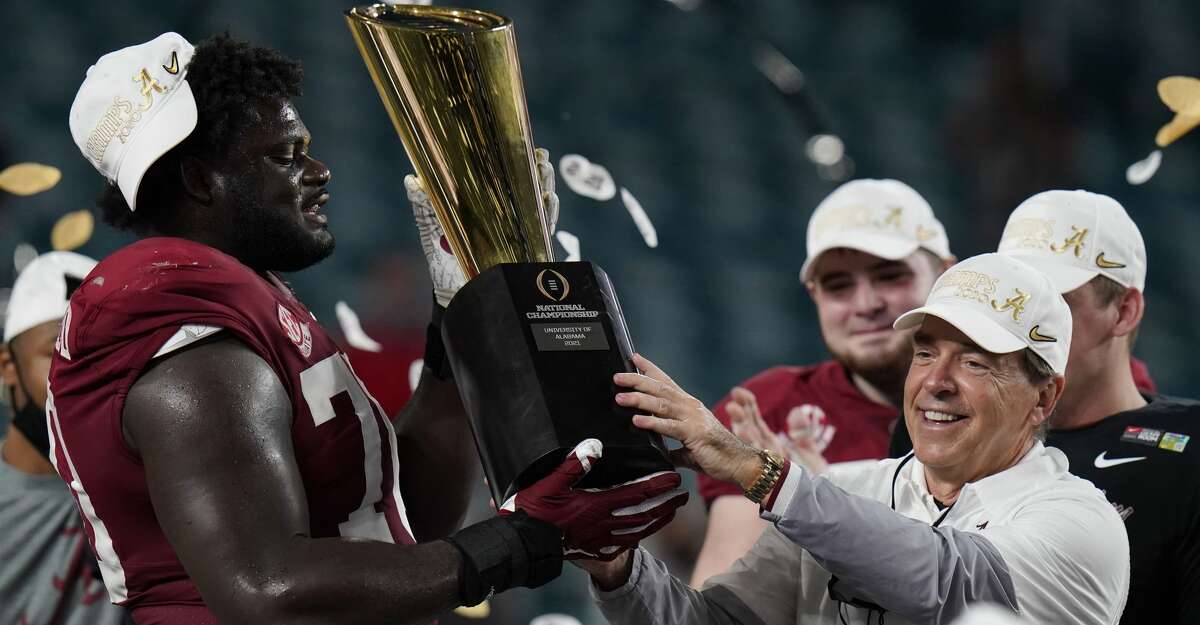 Alabama head coach Nick Saban and offensive lineman Alex Leatherwood hold the trophy after their win against Ohio State in an NCAA College Football Playoff national championship game, Tuesday, Jan. 12, 2021, in Miami Gardens, Fla. Alabama won 52-24. (AP Photo/Chris O'Meara)