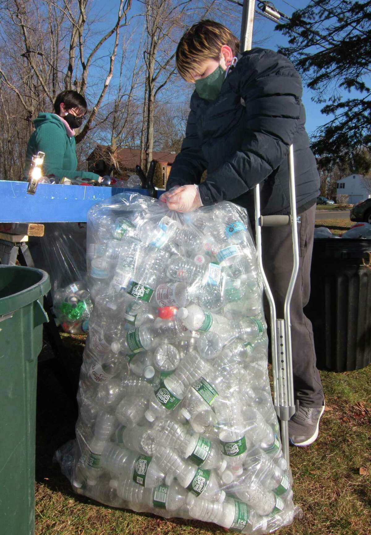 Scout Tim Andrade, 12, ties a full bag of plastic bottles during Boy Scout Troop 25's monthly redeemable bottle and can drive at First United Methodist Church in Shelton, Conn., on Saturday Jan. 9, 2021. The event, which helps raise money for scouting activities, is held each first Saturday of each month from 10 a.m. to 1 p.m.