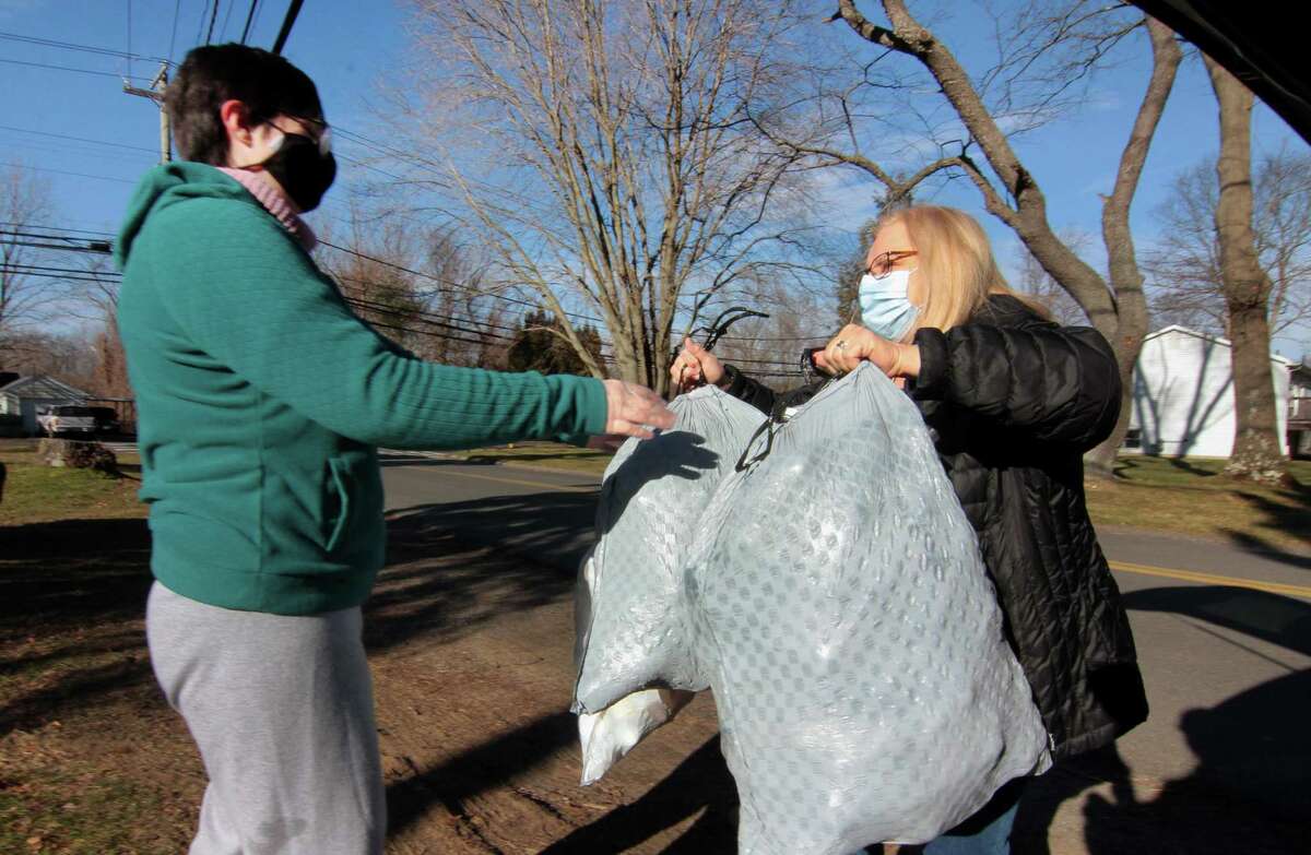 Meg Andrade, left, receives a donation of plastic bottles from resident Anna Pannella during Boy Scout Troop 25's monthly redeemable bottle and can drive at First United Methodist Church in Shelton, Conn., on Saturday Jan. 9, 2021. The event, which helps raise money for scouting activities, is held each first Saturday of each month from 10 a.m. to 1 p.m.
